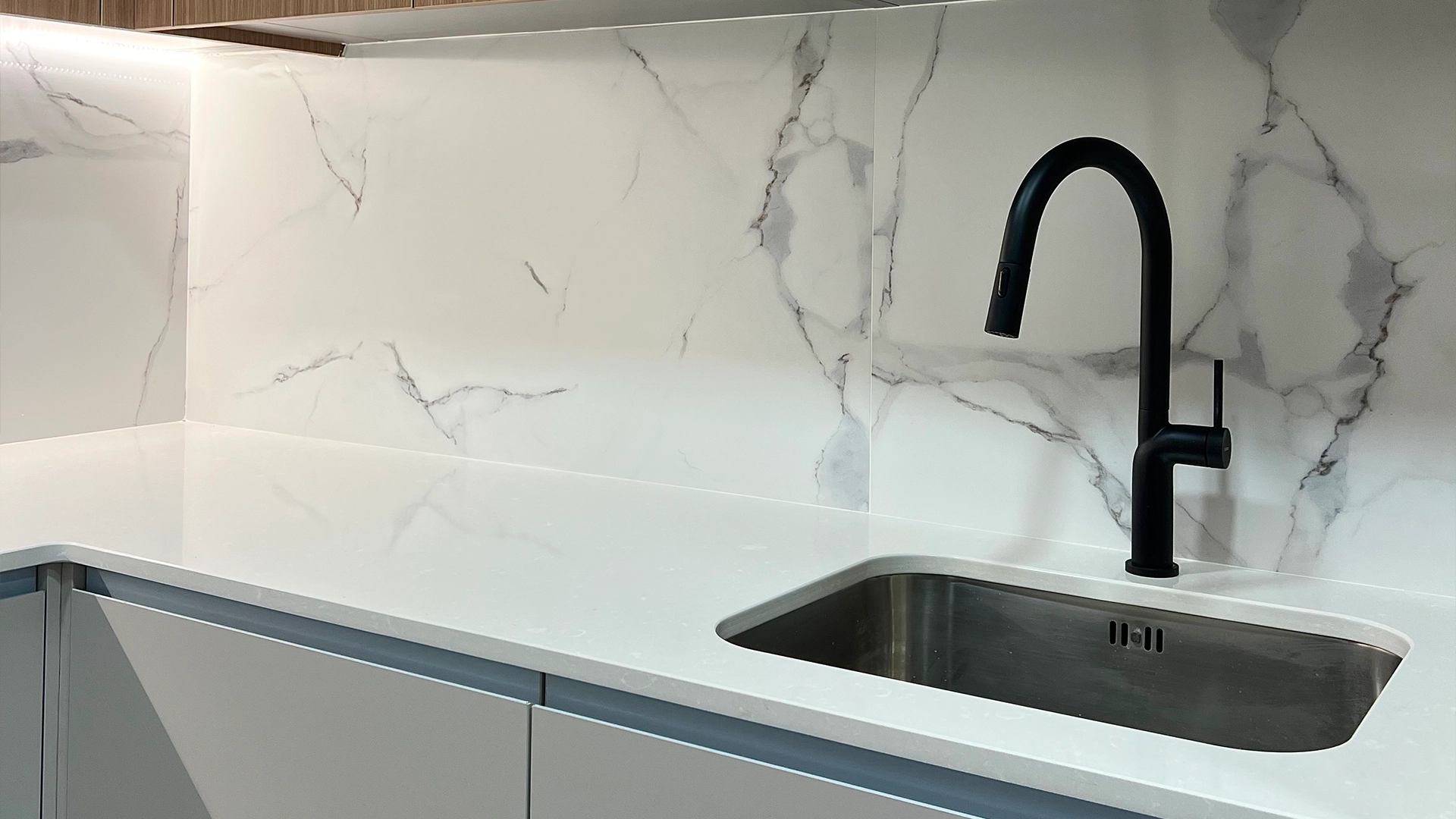 Reforma integral de la cocina de un piso de Barcelona con grifería monomando en negro y encimera blanca y gris.
