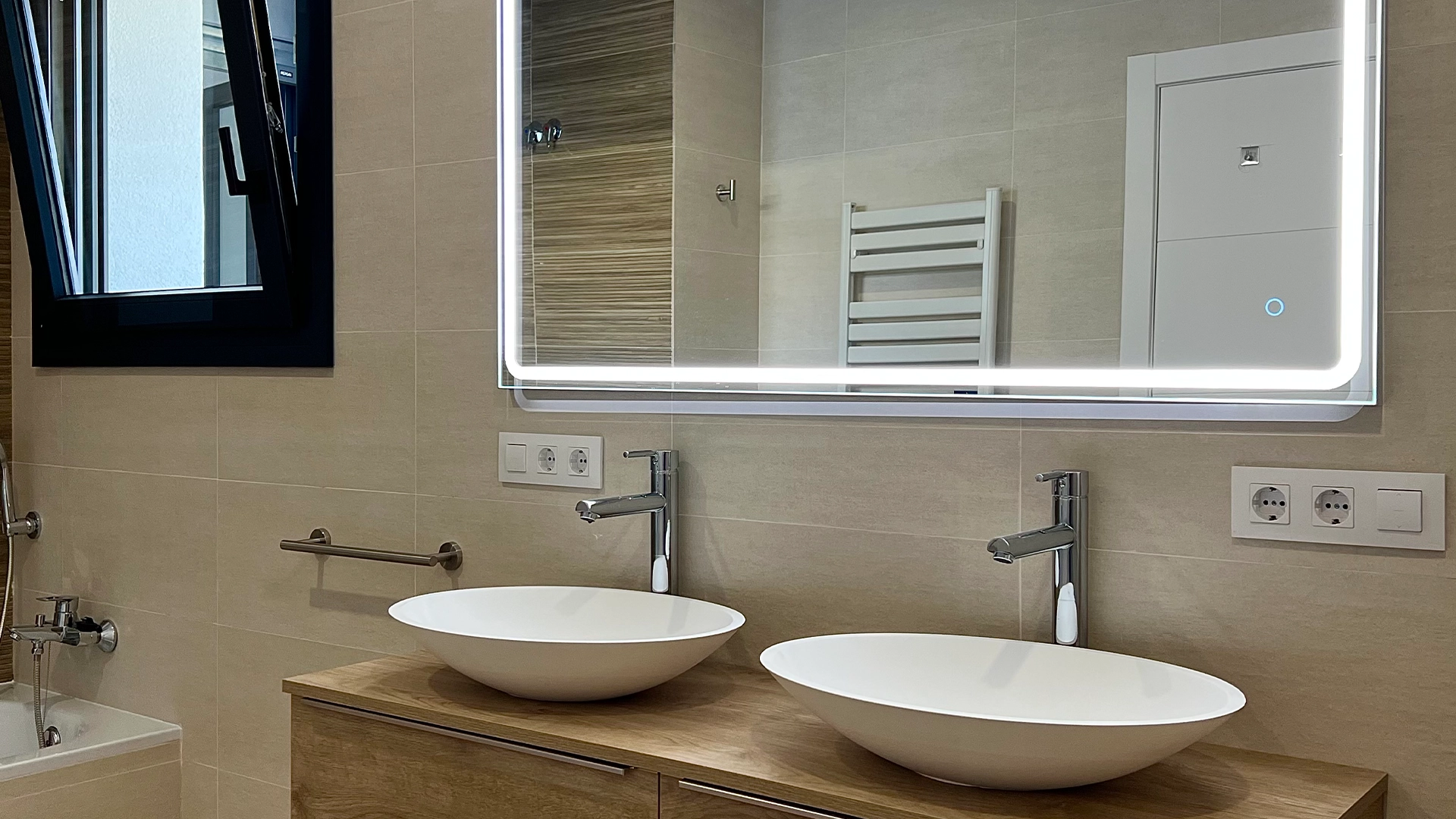 Cuarto de baño moderno con dos lavabos de sobremesa y espejo iluminado con LEDS.