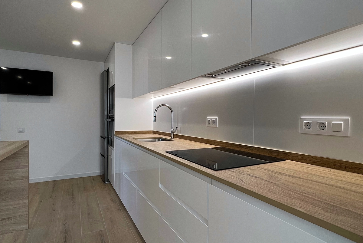 Reforma de la cocina de un piso en Sant Boi con muebles blancos y detalles de madera.