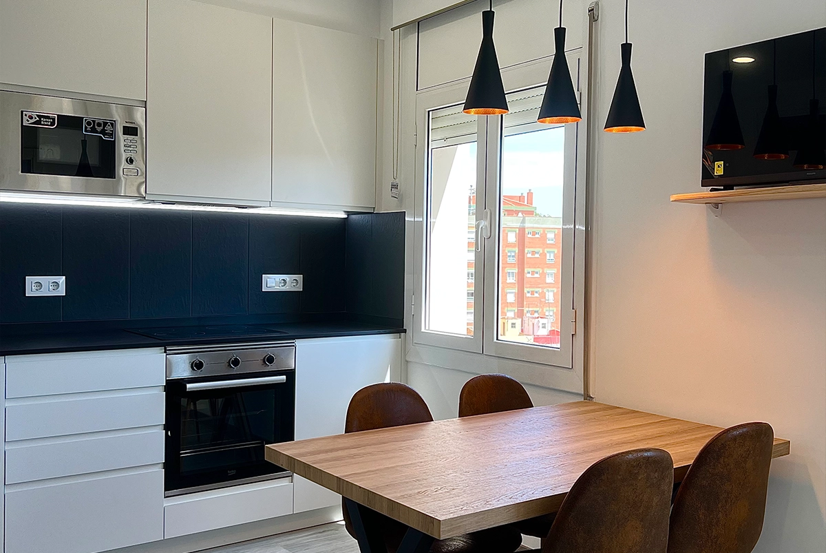 Cocina moderna en blanco y negro con mesa de madera.