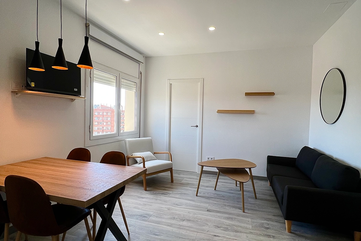 Piso pequeño reformado en Barcelona con cocina abierta y suelo de parquet en tonos claros de madera.